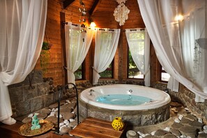 A wooden cabin with a stone interior, a hot tub, and white curtains. - Curry (Ramot)