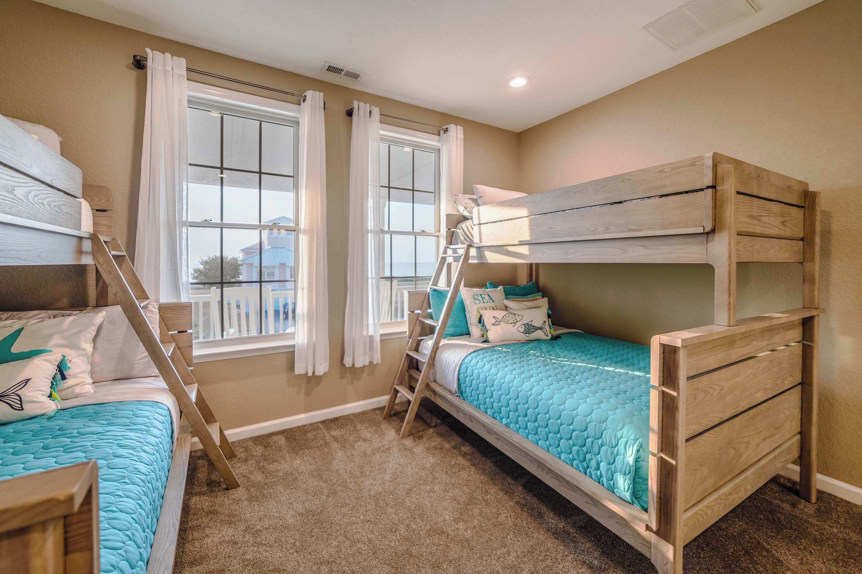 Una habitación con dos literas, una escalera y una ventana con cortinas.