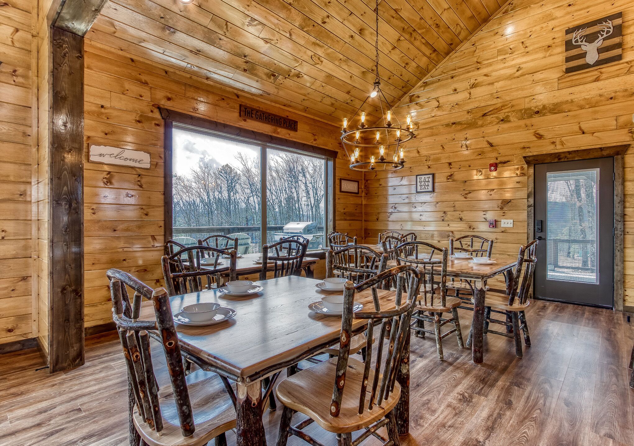 Un intérieur en bois avec un coin repas agrémenté de chaises rustiques et d’un lustre.