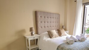 Ein Schlafzimmer mit einem großen Bett, zwei Nachttischen und einem Fenster mit Vorhängen.
