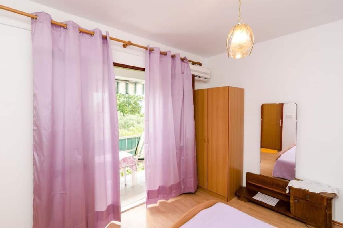 A bedroom with a bed, wooden wardrobe, and a mirror.