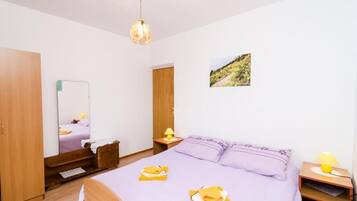 A bedroom with a bed, a wooden wardrobe, a nightstand with a lamp, and a wall-mounted picture.