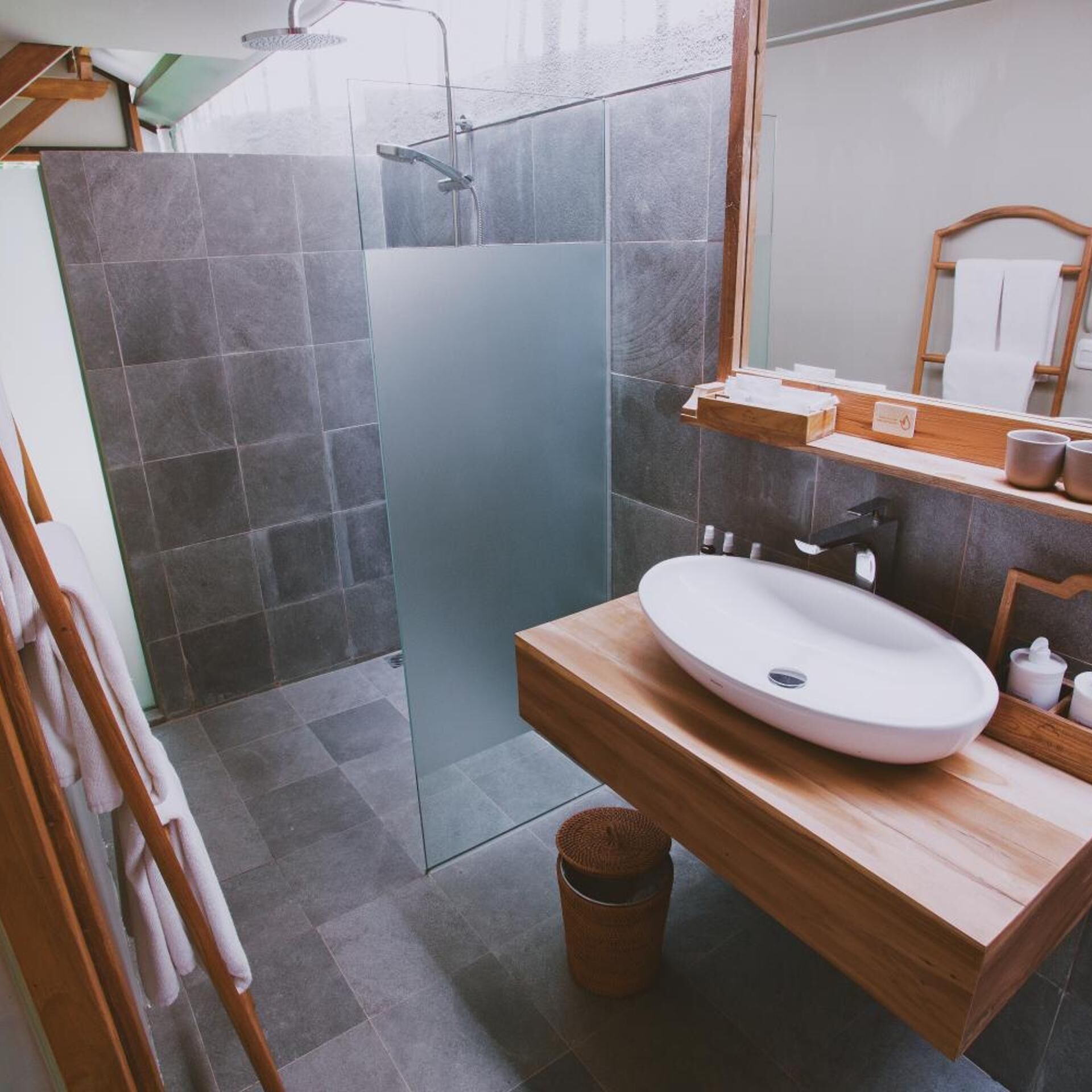 A modern bathroom with a glass shower enclosure, a wooden vanity with a sink, and a mirror.
