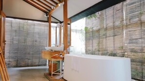 A modern bathroom with a freestanding bathtub, wooden beams, and a large window with blinds. - Ayom Java (Surakarta)