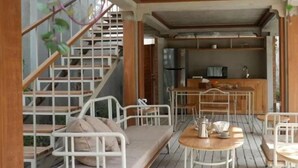 A modern interior with a staircase, a kitchen area, and a seating area with a table and chairs. - Ayom Java (Surakarta)
