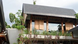 A modern building with a flat roof, wooden beams, and a balcony with plants. - Ayom Java (Surakarta)