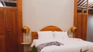 A bedroom with a wooden bed, white bedding, and two bedside lamps. - Ayom Java (Surakarta)