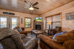 A cozy cabin interior with a fireplace, comfortable seating, and a television. - Stunning retreat: resort pool, theater, games, and mountain views for groups (Pigeon Forge)