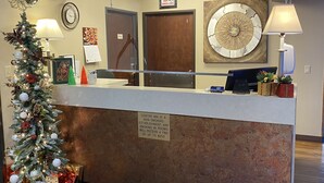 A hotel reception area with a Christmas tree, a clock, and a sign indicating a non-smoking policy. - The Center Inn (Sioux Falls)
