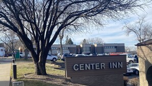 A sign for Center Inn with a parking lot and buildings in the background. - The Center Inn (Sioux Falls)