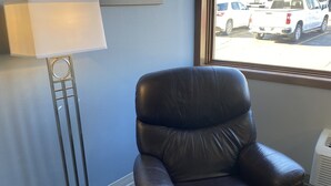 A black leather chair, a floor lamp, and a window with a view of parked cars. - The Center Inn (Sioux Falls)