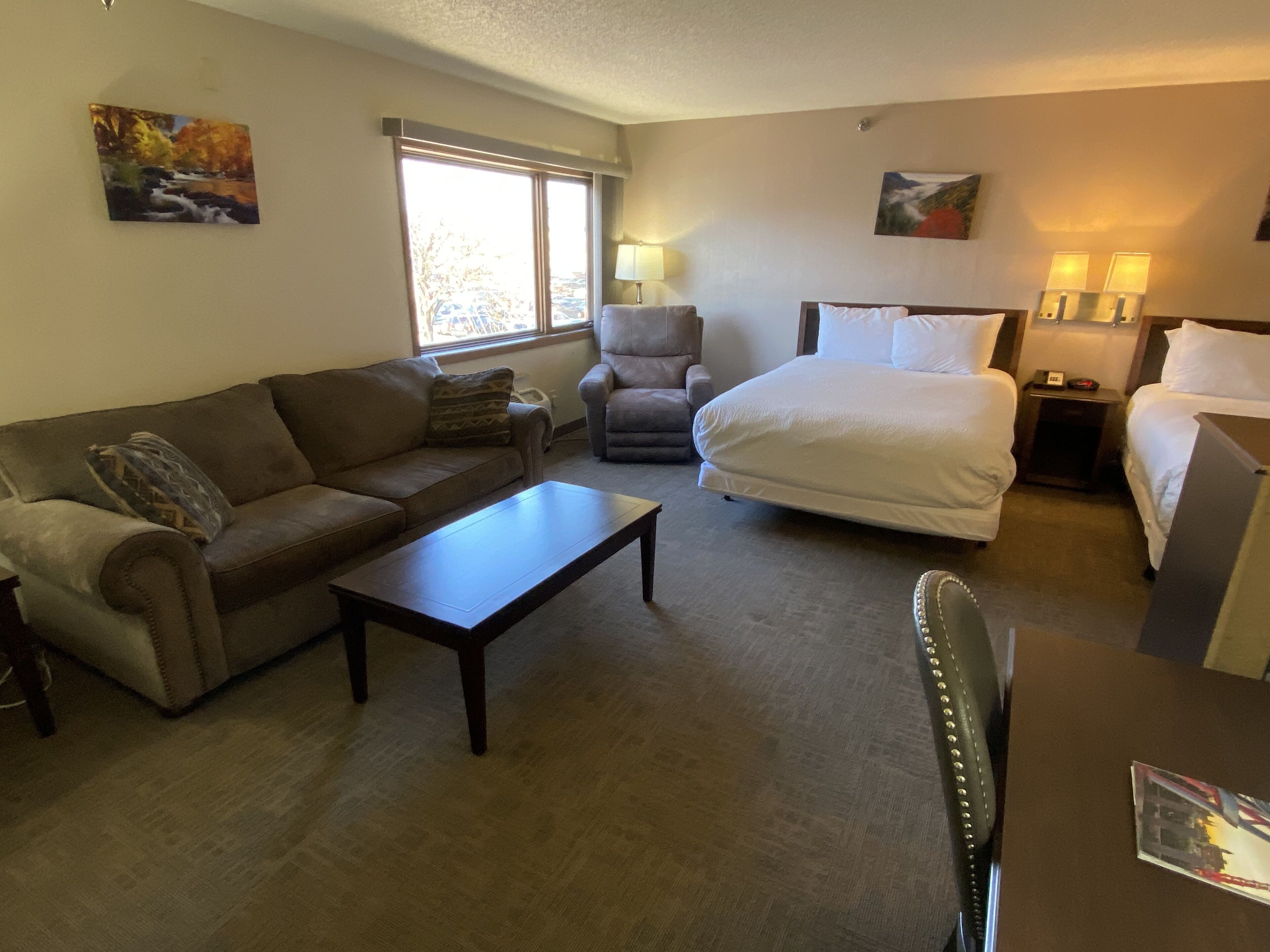 A hotel room with a bed, a sofa, a chair, a coffee table, and a desk.