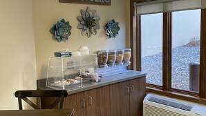 A bakery counter with a 'welcome' sign, decorative flowers, and a window view.