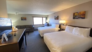 A hotel room with two beds, a desk with a computer, a television, and a couch.