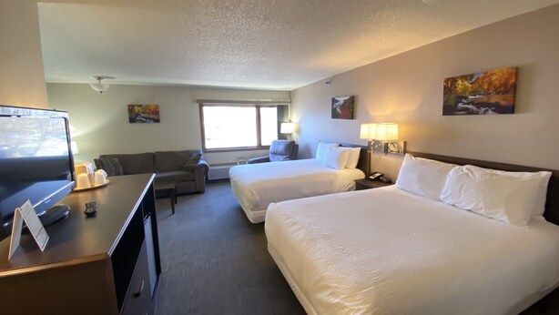 A hotel room with two beds, a desk with a computer, a television, and a couch. - The Center Inn (Sioux Falls)