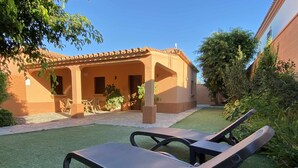 Un patio con mesa de billar, sillones de descanso y un edificio con tejado de tejas.