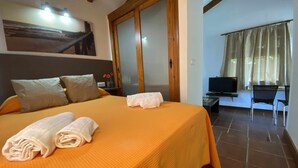 Una habitación de hotel con una cama grande, televisión y un escritorio con silla.