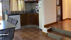 Una cocina con armarios de madera, lavadora, microondas y comedor con mesa y sillas.