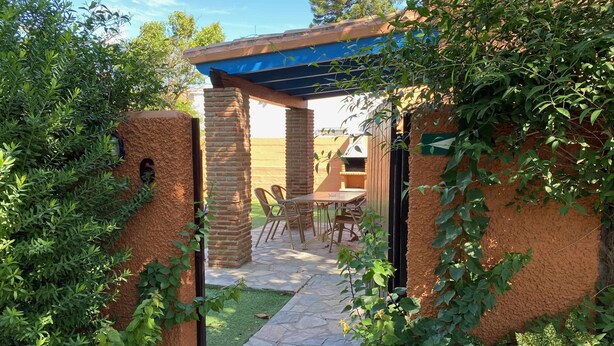 Un patio con pérgola, suelo de piedra y un conjunto de asientos.