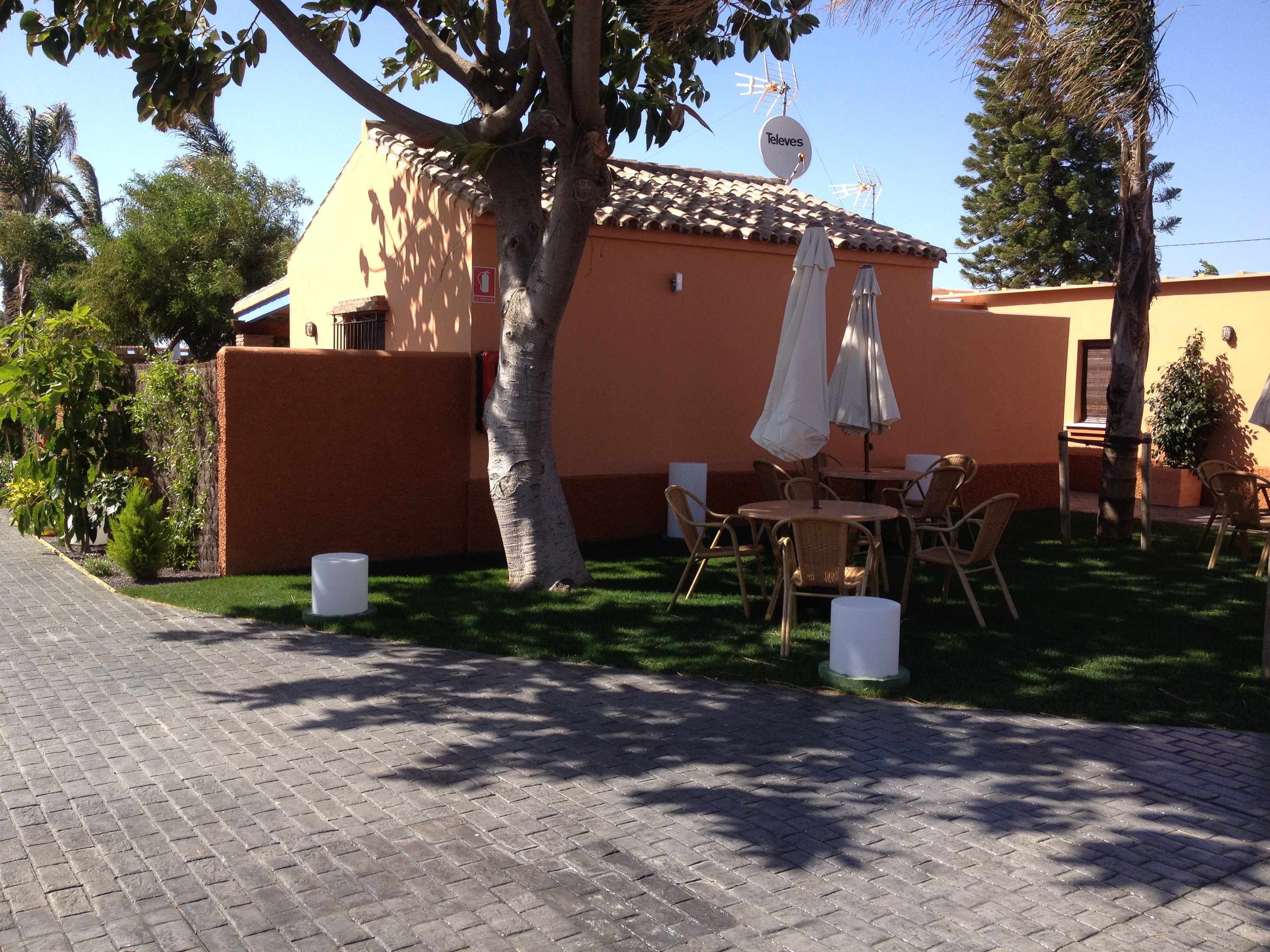 An outdoor seating area with tables and chairs, a satellite dish, and a paved walkway.