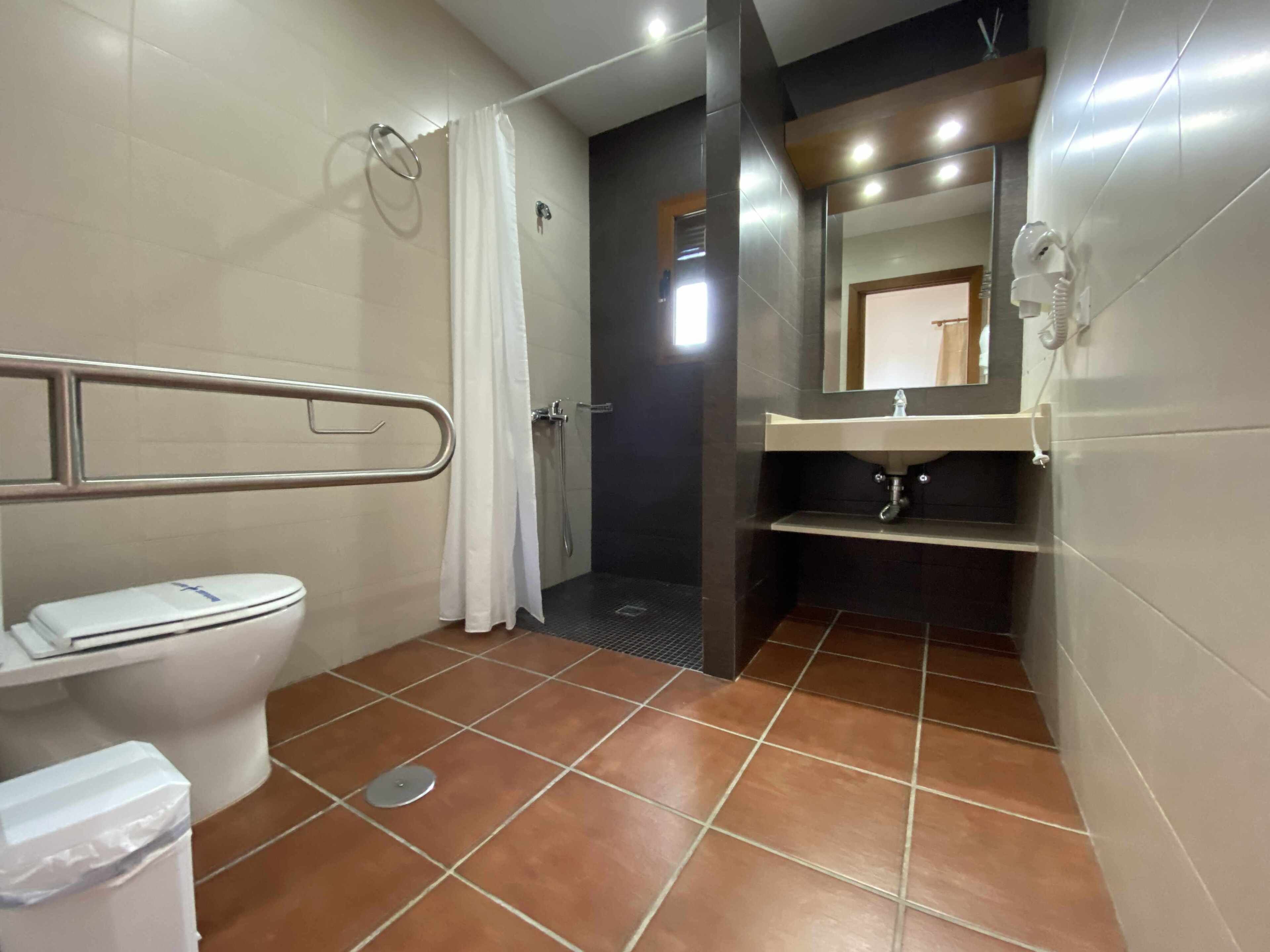 A bathroom with a toilet, shower, and sink.