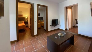 A modern hotel room with a bed, a desk, a TV, and a dining area. - Apartamento con Doble Entrada y Piscina Compartida en el Palmar (Palmar, El)