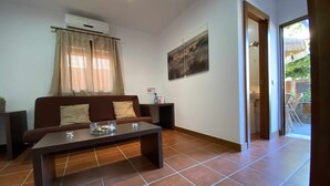 A living room with a brown sofa, a coffee table, and a painting on the wall. - Apartamento con Doble Entrada y Piscina Compartida en el Palmar (Palmar, El)