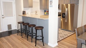 A modern kitchen with a central island, stainless steel appliances, and a bar stool area. - Riverside Island Bungalow (Daytona Beach)
