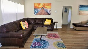 A living room with a brown leather couch, a wooden coffee table, and a colorful rug. - Riverside Island Bungalow (Daytona Beach)