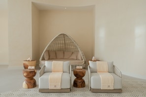 A modern lounge area with a hanging chair, two armchairs, and a small side table.