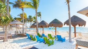 A beachside resort with thatched umbrellas, wooden deck, and colorful lounge chairs. - Garza Blanca Resort & Spa Cancun (Punta Sam)