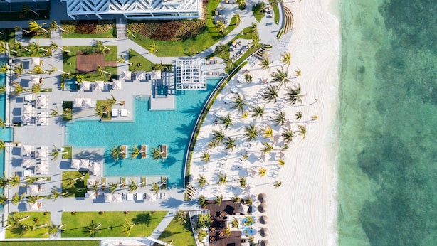 An aerial view of a resort with a central swimming pool, multiple lounge areas, and a beachfront. - Garza Blanca Resort & Spa Cancun (Punta Sam)