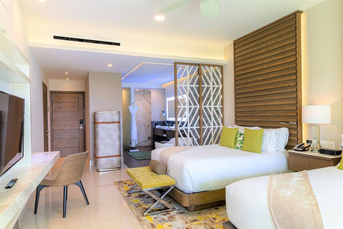 Habitación de hotel moderna con una cama grande, un escritorio y una silla. Se puede ver un baño al fondo.