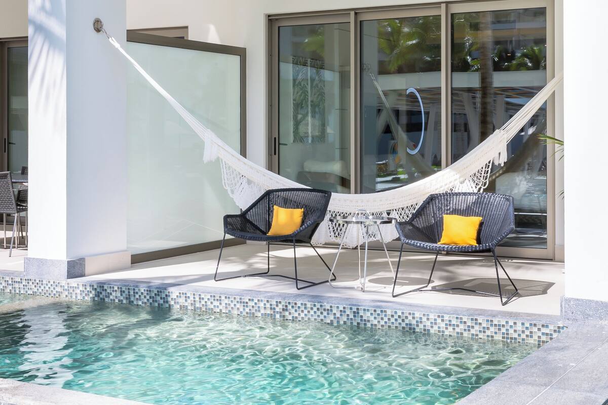 Un área de piscina con dos sillones de mimbre y una hamaca.