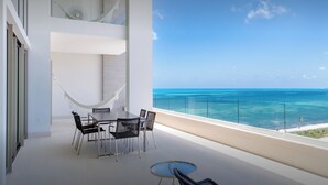 A balcony with a table and chairs, a hammock, and a view of the ocean. - Garza Blanca Resort & Spa Cancun (Punta Sam)