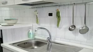 Una cocina moderna con un lavamanos de acero inoxidable, armarios blancos y encimera blanca.