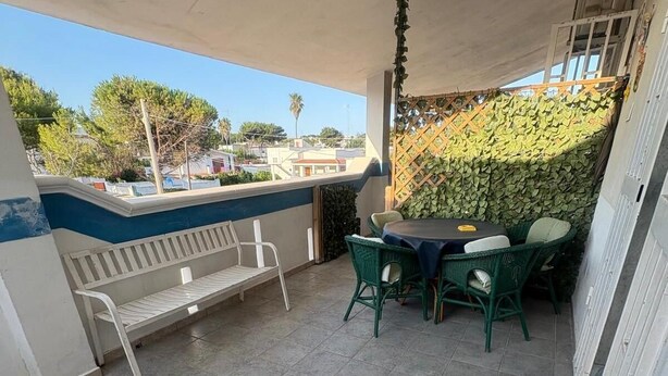 Un balcón con mesa y sillas, un banco y vistas del entorno.