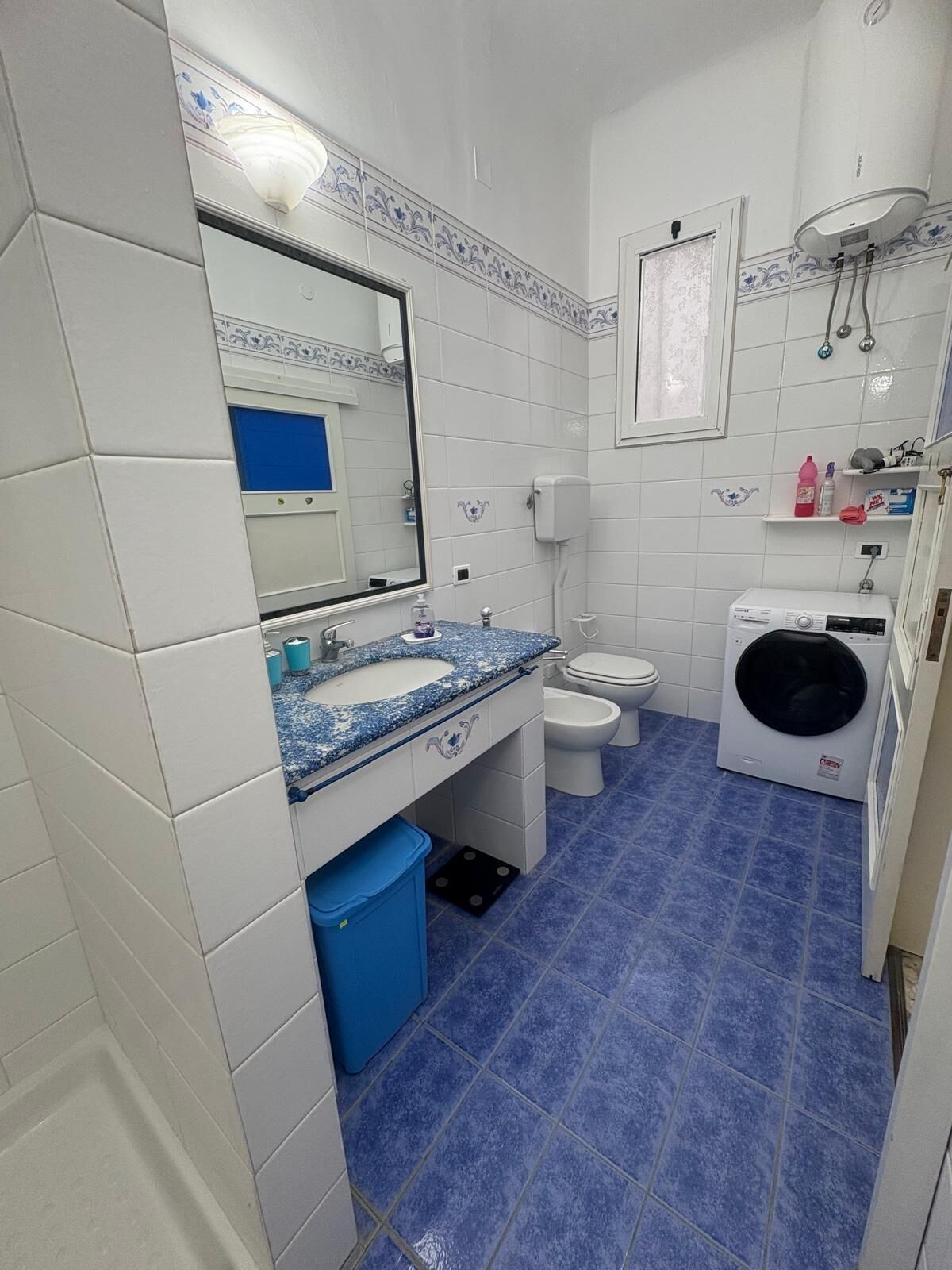 Un bagno dotato di lavandino, specchio, WC e lavatrice.
