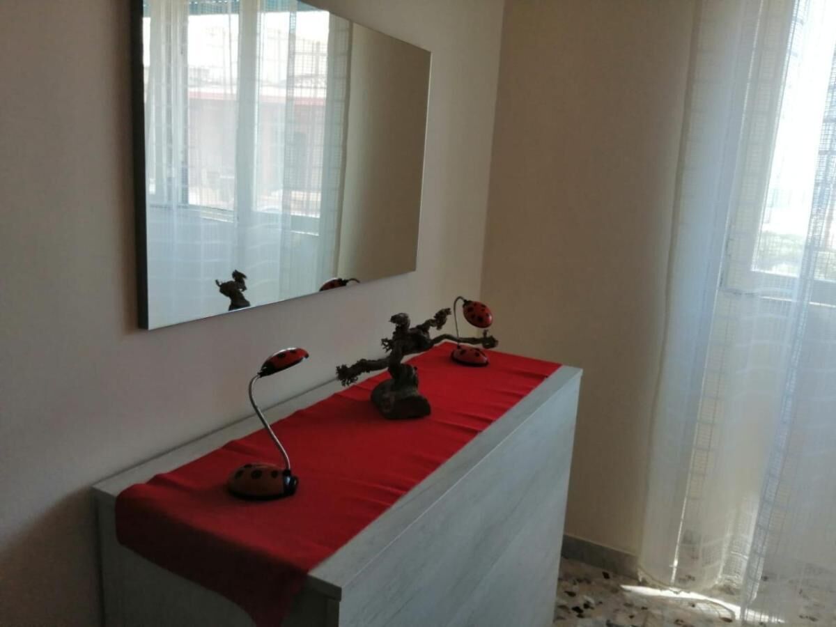 Une salle de bain avec un meuble-lavabo blanc, une serviette rouge et un miroir au-dessus.
