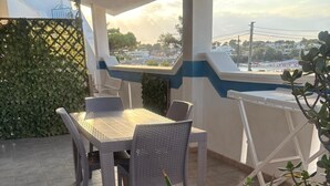 Une terrasse extérieure avec une table et des chaises, entourée de plantes et offrant une vue sur le paysage urbain.