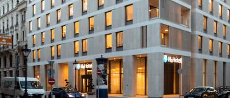 Un hotel moderno con varios pisos, ventanas amplias y un llamativo letrero que dice 'Hotel'.
