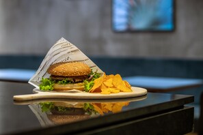 A burger and chips on a plate with a newspaper underneath, placed on a reflective surface. - Danubius Hotel District V (Budapest)