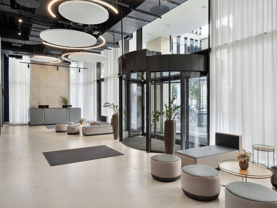 Un vestíbulo moderno con puerta giratoria, zonas de estar y mostrador de recepción.
