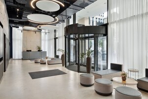 Un vestíbulo moderno con puerta giratoria, zonas de estar y mostrador de recepción.