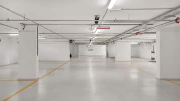 A clean, empty parking garage with white walls, concrete floors, and yellow parking lines.