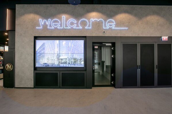 A modern building with a 'Welcome' sign and a large window displaying a cityscape. - Danubius Hotel District V (Budapest)