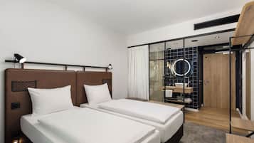 Quarto de hotel com duas camas, um espelho grande, um closet espaçoso e um box de chuveiro.