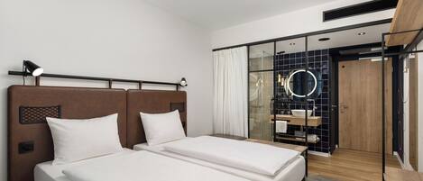 A hotel room with two beds, a large mirror, a walk-in closet, and a shower area.