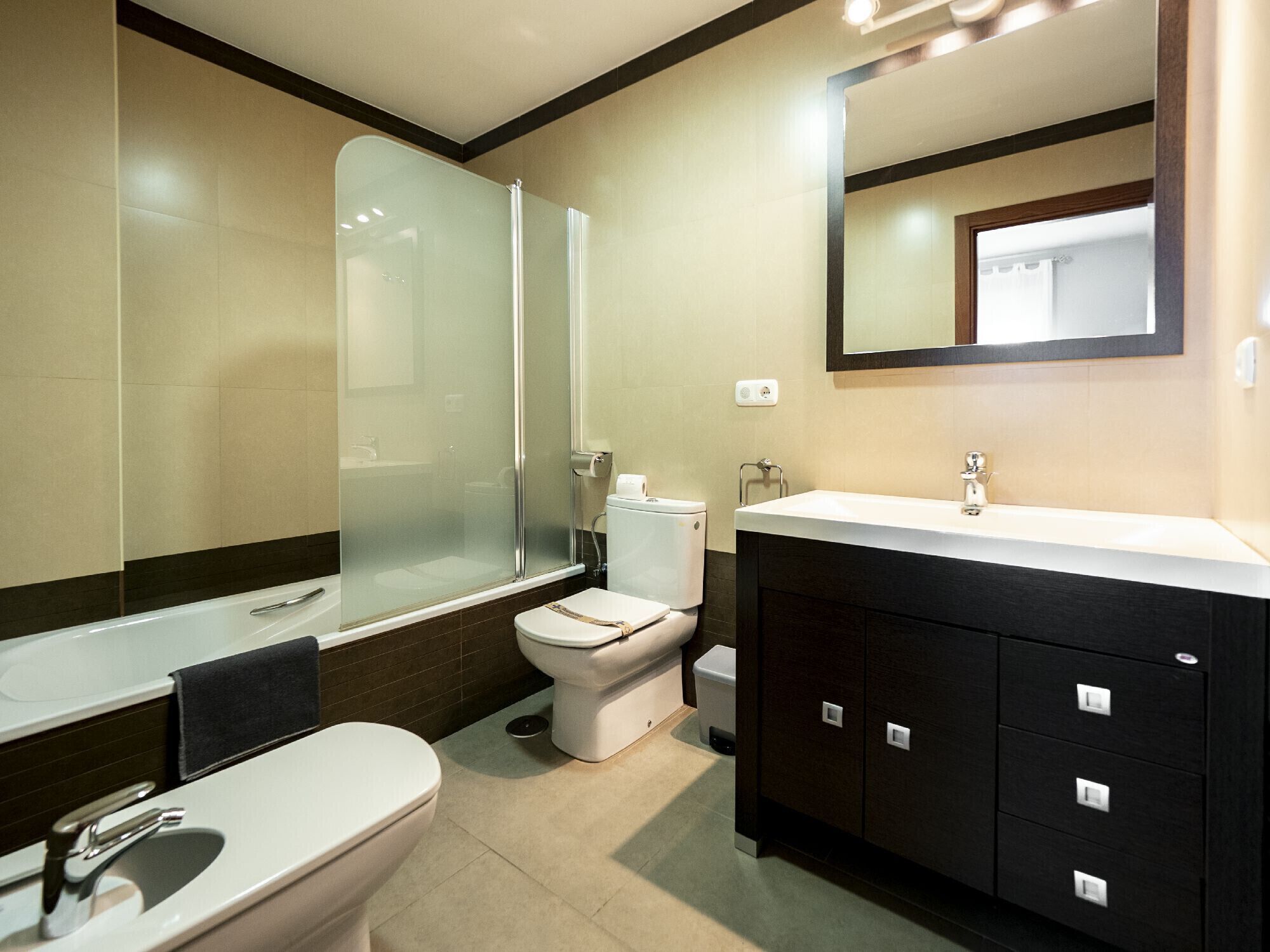 Een moderne badkamer met een douchecabine van glas, een toilet, een wastafel en een badkamermeubel met kastjes.