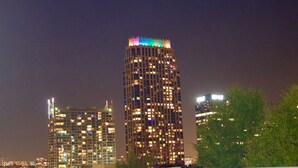 Ein Hochhaus mit beleuchteten Fenstern und einer farbenfrohen Lichtinstallation auf dem Dach.